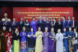 Party General Secretary To Lam and his spouse, staff of the Vietnamese Embassy and representatives of the Vietnamese community in a group photo at their meeting in Vientiane on December 1 evening. (Photo: VNA)