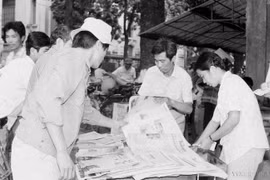 Residents of the capital buy and read the "Tin tuc buoi chieu" (afternoon news) newspaper, published by the Vietnam News Agency (VNA), to stay updated on the closing session of the 7th National Congress of the Communist Party of Vietnam (July 17, 1991). (Photo: VNA)