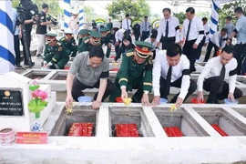 PM Pham Minh Chinh (first, left) and officials scatter flowers and earth to rebury martyrs' remains at the ceremony at the Doc Ba Dac cemetery in Thoi Son ward, An Giang province, on July 21. (Photo: VNA)