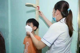 A health worker measures a boy's height as part of a screening programme to promptly detect children with malnutrition problems. (Photo: vtv.vn)