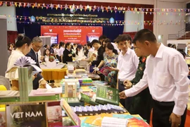 Delegates visit the book display booth of the Vietnamese Embassy in Laos. (Photo: VNA)