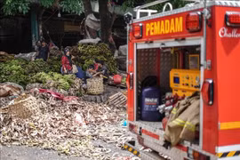 Traders move fruits and vegetables out of the Kramat Jati market in Jakarta, Indonesia, after a fire on December 15 (Photo: XINHUA/VNA)