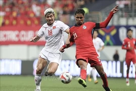 Thanh Binh (white's dribbling is fiercely blocked by a Singaporean defender at the first leg of the ASEAN Cup semifinal on December 26. (Photo: VNA)