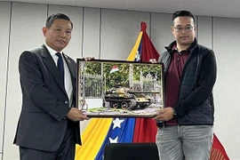 Vietnamese Ambassador to Venezuela Vu Trung My (left) presents a photo of the April 30 victory to a representative of the Antonio Jose de Sucre International Youth Leadership Training School. (Photo courtesy of the Vietnamese Embassy in Venezuela)