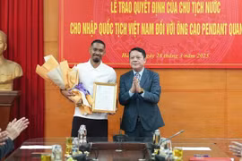 A representative of the Hanoi Department of Justice hands over the decision to footballer Cao Pendant Quang Vinh (left). (Photo: nhandan.vn)