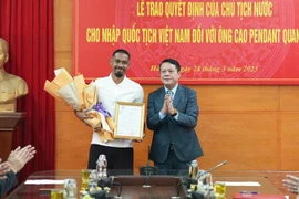 A representative of the Hanoi Department of Justice hands over the decision to footballer Cao Pendant Quang Vinh (left). (Photo: nhandan.vn)