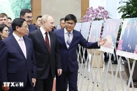 Prime Minister Pham Minh Chinh (L) and Russian President Vladimir Putin (C) visit a photo exhibition showcasing cooperation between the two countries. (Photo: VNA)