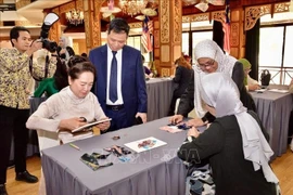 National Assembly (NA) Chairman Tran Thanh Man’s spouse, Nguyen Thi Thanh Nga (left) and Datin Dr. Rozana binti Kamal, spouse of the Speaker of the Malaysian House of Representatives, experience traditional fabric printing and painting. (Photo: VNA).