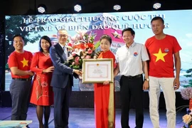 Vietnamese Ambassador to Germany Vu Quang Minh presents a certificate of merit and flowers to Bui Thi Thu Minh, head of the Vietnamese Liaison Committee in Europe "For Vietnam's Seas and Islands", President of the Truong Sa Club in Germany. (Photo: VNA) 