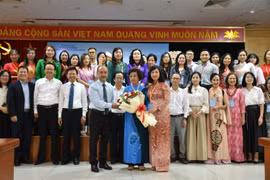 Chairman of the State Committee for Overseas Vietnamese (L) presents flowers to representatives of Vietnamese language teachers abroad. (Photo: VNA)