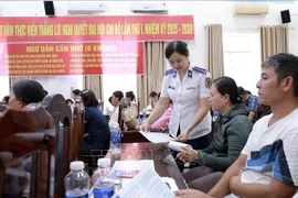 Officers of Coast Guard Region 4 distribute information leaflets to local fishermen. (Photo: VNA)