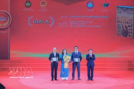 Head of the Party Central Commitee's Commission for Information, Education and Mass Mobilisation Trinh Van Quyet (first, right) presents A prize to the winning authors and groups of authors. (Photo: VNA)