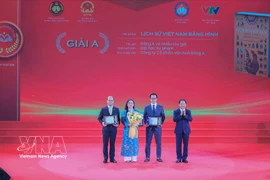 Head of the Party Central Commitee's Commission for Information, Education and Mass Mobilisation Trinh Van Quyet (first, right) presents A prize to the winning authors and groups of authors. (Photo: VNA)