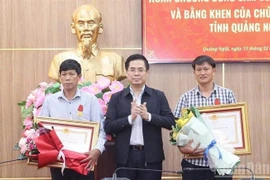 Chairman of the Quang Ngai provincial People's Committee Nguyen Hoang Giang (centre) presents the State President's Bravery Order to two citizens of Ly Son special zone on December 15. (Photo: VNA)