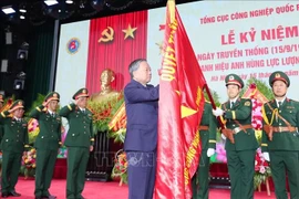 Party General Secretary To Lam sticks the Hero of the People's Armed Forces badge to the traditional flag of the General Department of Defence Industry. (Photo: VNA)