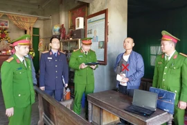 A policeman reads an order to detain Le Minh Vu (Photo: VNA)