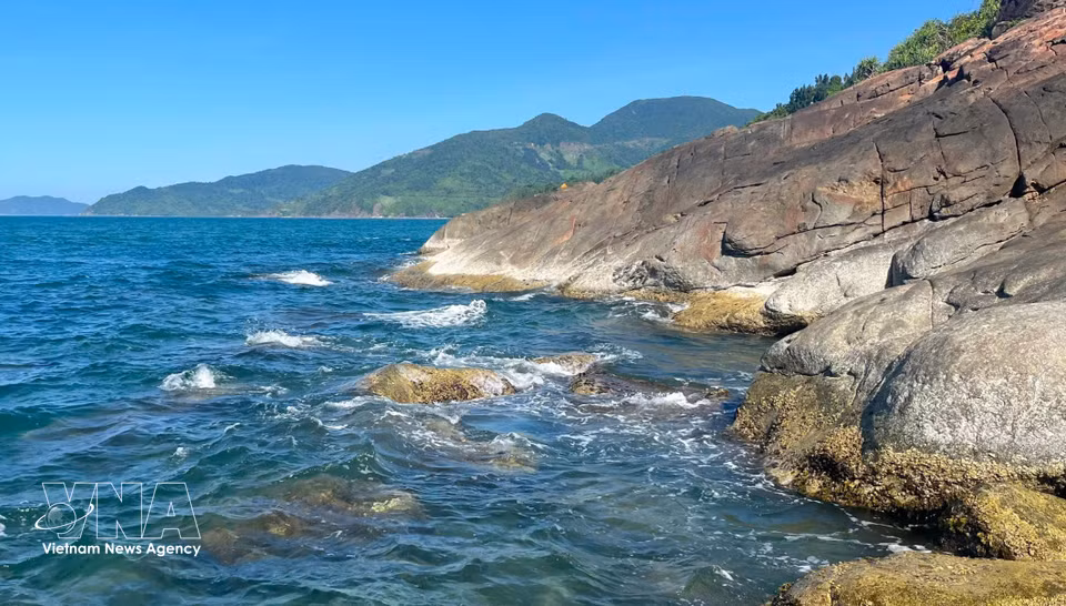 Dark grey rocks lying beneath Hai Van Pass resemble nature's rough-hewn pieces, contrasting beautifully with the tranquil blue sea. (Photo: VNA)