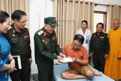 Major General Vo Van Chot, head of Nghe An province’s liaison board for former Vietnamese volunteer soldiers and military experts in Laos, presents a gift to a patient at Military Central Hospital 103 of Laos. (Photo: VNA)