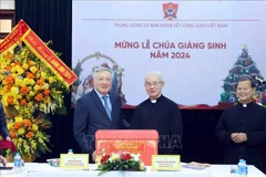 Standing Deputy Prime Minister Nguyen Hoa Binh (left) presents a X-mas gift to the Central Committee for Solidarity of Vietnamese Catholics on December 22. (Photo: VNA)