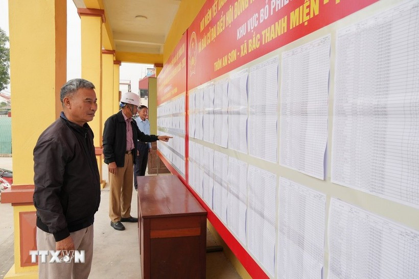 Voters review the lists of candidates and their brief biographies. (Photo: VNA) 