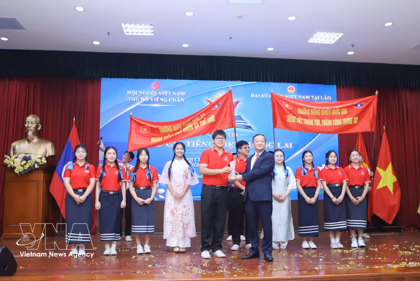 Ambassador Nguyen Minh Tam presents the first prize to the team from the National University of Laos' School of Gifted and Ethnic Students at the contest. (Photo: VNA)