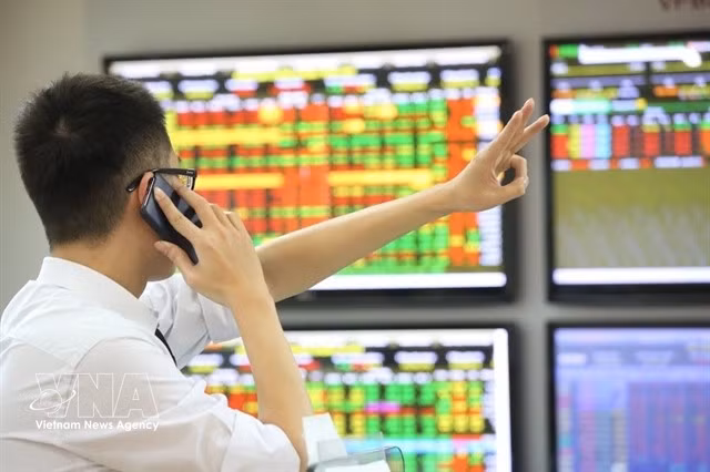 An investor talks on the phone while watching market movements. (Photo: VNA)