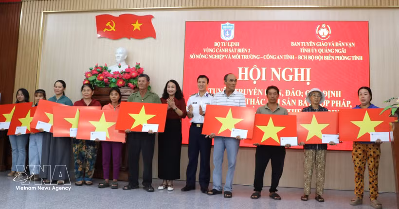 Representatives from the Coast Guard Region 2 Command and the Quang Ngai provincial Party Committee’s Board for Information, Education and Mass Mobilisation give gifts and national flags to fishermen. (Photo: VNA)