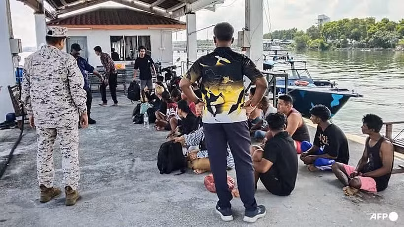 A Malaysian Maritime Enforcement Agency staff member checks on survivors rescued during a search and rescue operation off the coast of Pangkor Island in Perak on May 12, 2026, after a boat carrying migrants capsized. (Photo: AFP/Malaysian Maritime Enforcement Agency)