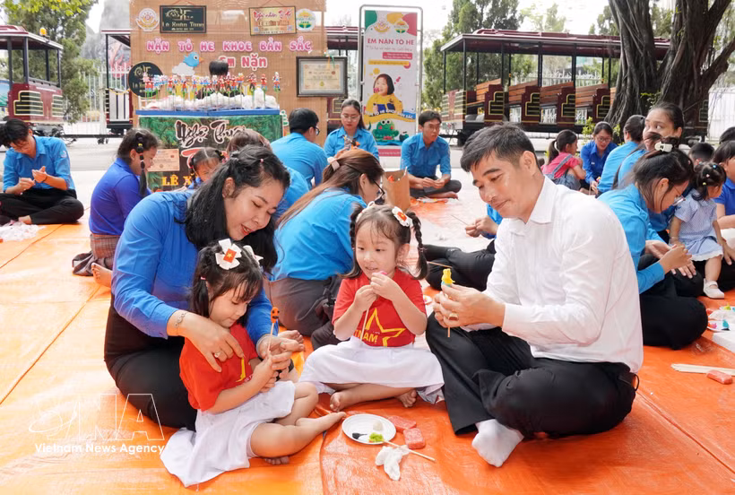 A family makes traditional "to he" figurines at the 2026 Happy Family Festival (Photo: VNA)