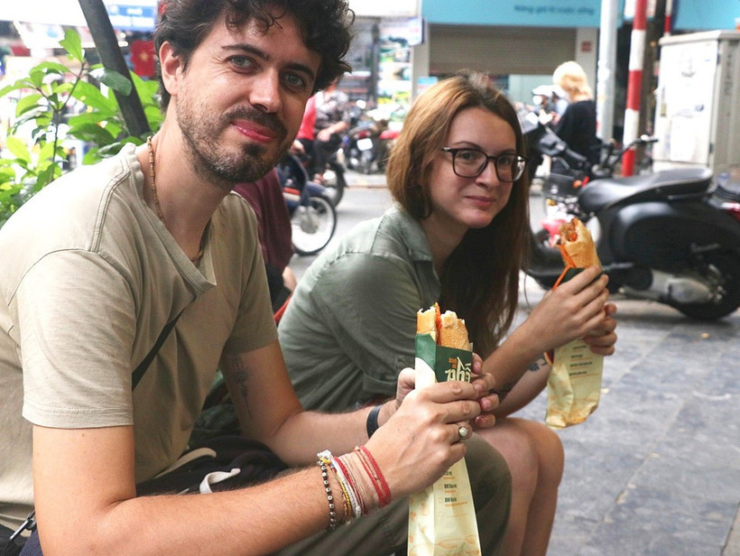 Foreign visitors enjoy "banh mi" in Hanoi (Photo: VNA)