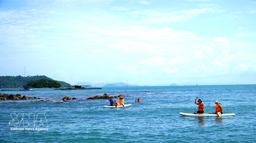 Tourists enjoy stand-up paddleboarding (SUP) and foraging for seafood along the waters of the Hai Tac Archipelago. (Photo: VNA)