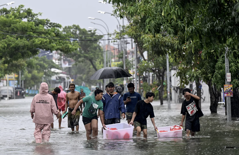 People move their belongings through an inundated street amid floods following heavy rain in Indonesia's resort island of Bali on February 24, 2026. (Photo: AFP)