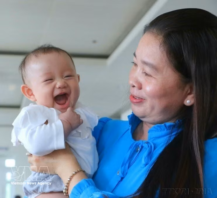 A child accompanies her mother to receive a certificate of merit honouring exemplary families with two daughters, at a ceremony organised in then Hau Giang province on January 5, 2023. (Photo: VNA) 