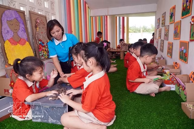 A teacher and children at Tran Cao Kindergarten in Quang Hung commune, Hung Yen province, take part in experiential learning activities. (Photo: VNA)