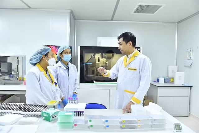 Dr. Vo Sy Nam (right) discusses genome sequencing technology with his colleagues. (Photo: VGP)