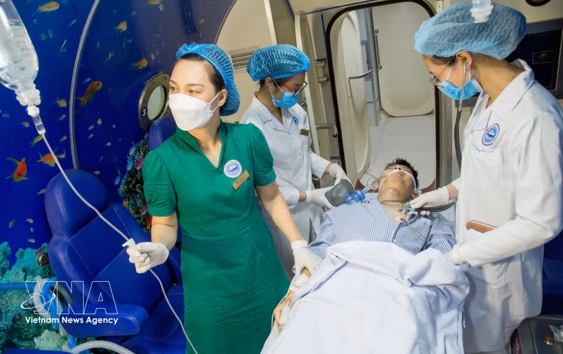 Medical workers of the Vietnam National Institute of Maritime Medicine gives treatment to a patient using hyperbaric oxygen therapy. (Photo: VNA)