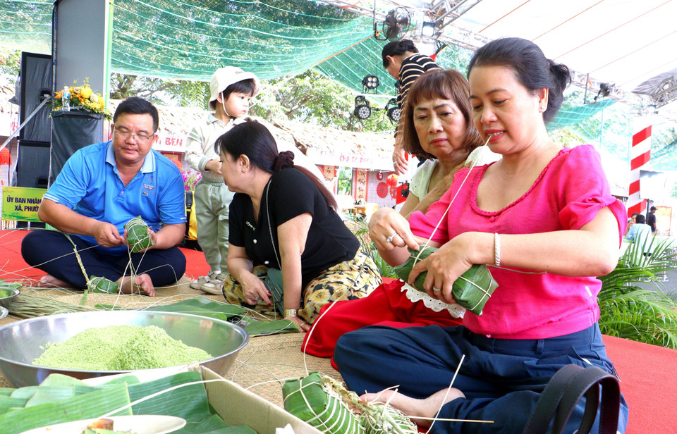 Visitors join local residents in wrapping traditional "banh tet" (Vietnamese cylindrical sticky rice cake). (Photo: VNA)