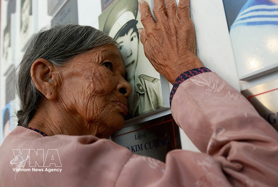 Ms. Ha Thi Lien from the central province of Ha Tinh, mother of fallen soldier Dao Kim Cuong, rests her face against her son’s portrait at the Gac Ma Martyrs’ memorabilia exhibition area within the Gac Ma Memorial Site. (Photo: VNA)