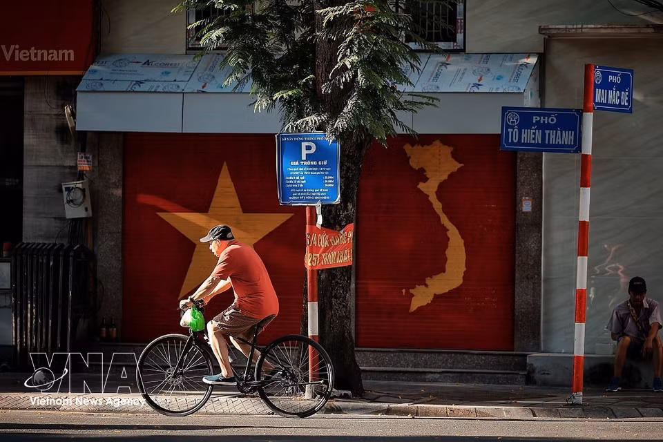 People cycle on the streets when the weather is still cool in the early morning. (Photo: VNA)