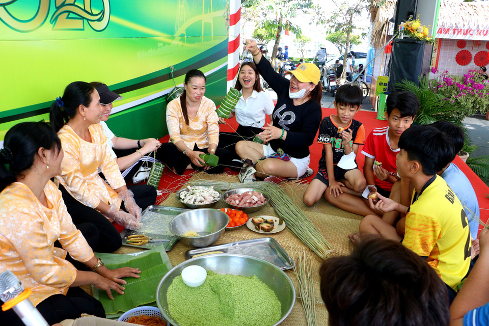 Visitors join local residents in wrapping traditional "banh tet" (Vietnamese cylindrical sticky rice cake). (Photo: VNA)