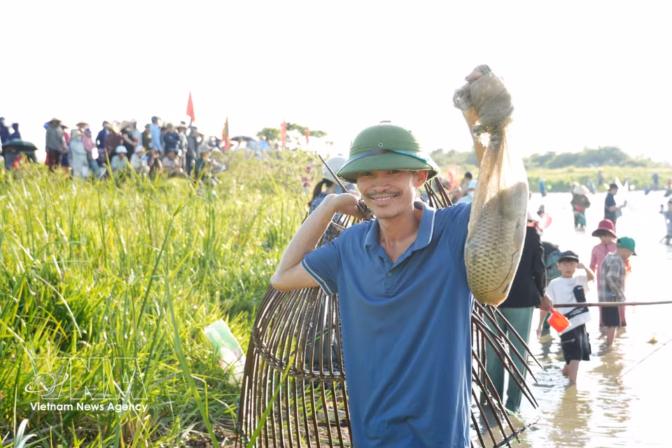 A participant proudly shows off his catch after taking part in traditional fishing activities. (Photo: VNA)
