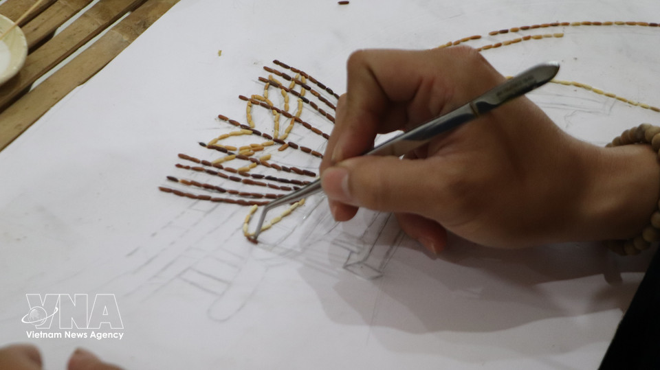 Khuu Tan Buu meticulously placing every grain to bring a rice painting to life. (Photo: VNA)