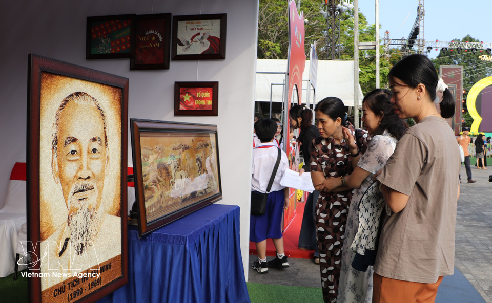 Visitors explore the unique textures and cultural themes of the rice art. (Photo: VNA)