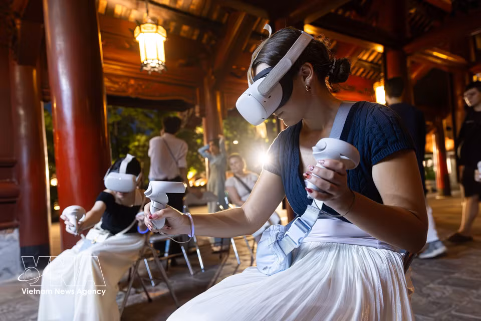 Foreign visitors use virtual reality (VR) headsets to explore heritage cultural spaces during a night tour. (Photo: Published by VNA) ​