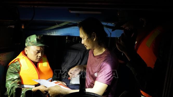A border guard of Gia Lai province examines fishing vessel documents. (Photo: VNA) 