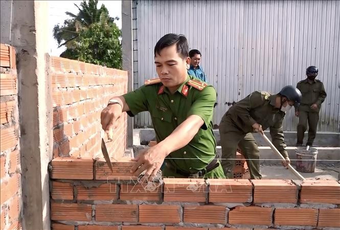 Police officers and soldiers help build a house for the needy. (Photo: VNA)