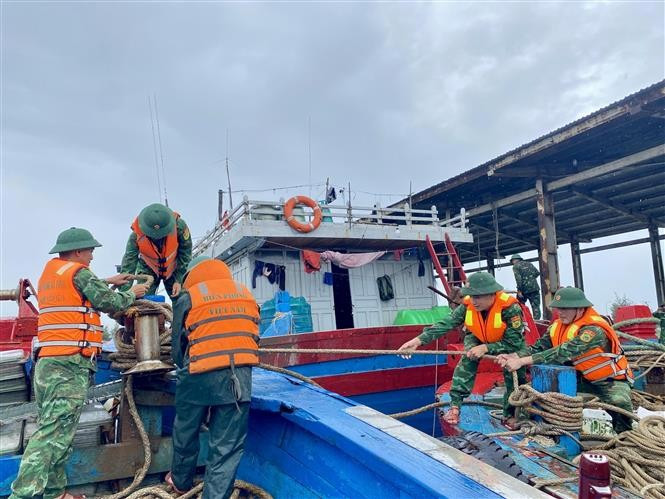 Border guards assist fishermen in reinforcing and securing their boats. (Photo: VNA)