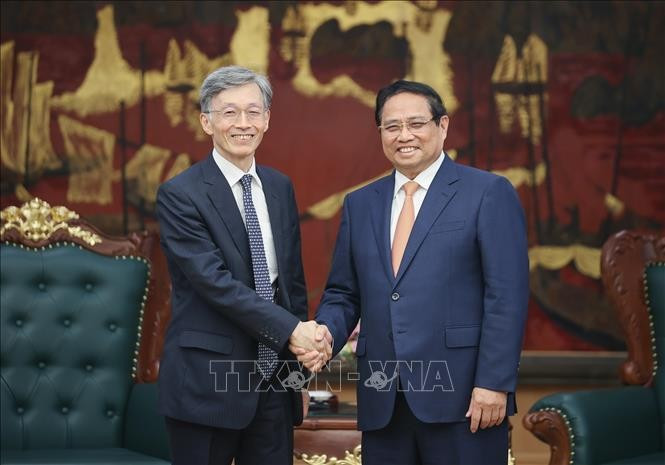 Prime Minister Pham Minh Chinh (R) welcomes Deputy Managing Director of the International Monetary Fund Kenji Okamura. (Photo: VNA)