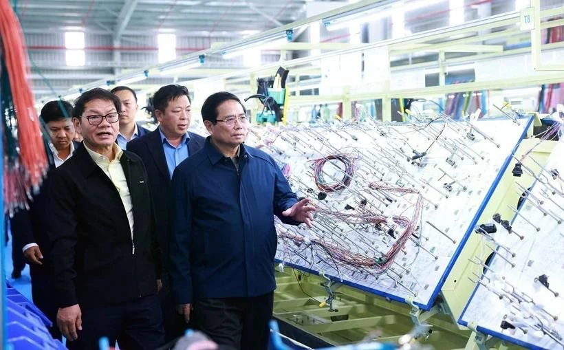 Prime Minister Pham Minh Chinh (R) visits a production line of an enterprise in Quang Nam last month. (Photo: VNA)