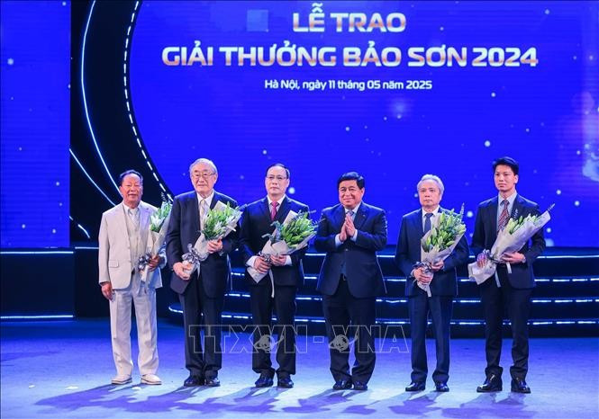 Deputy Prime Minister Nguyen Chi Dung presents flowers to congratulate the winners. (Photo: VNA)